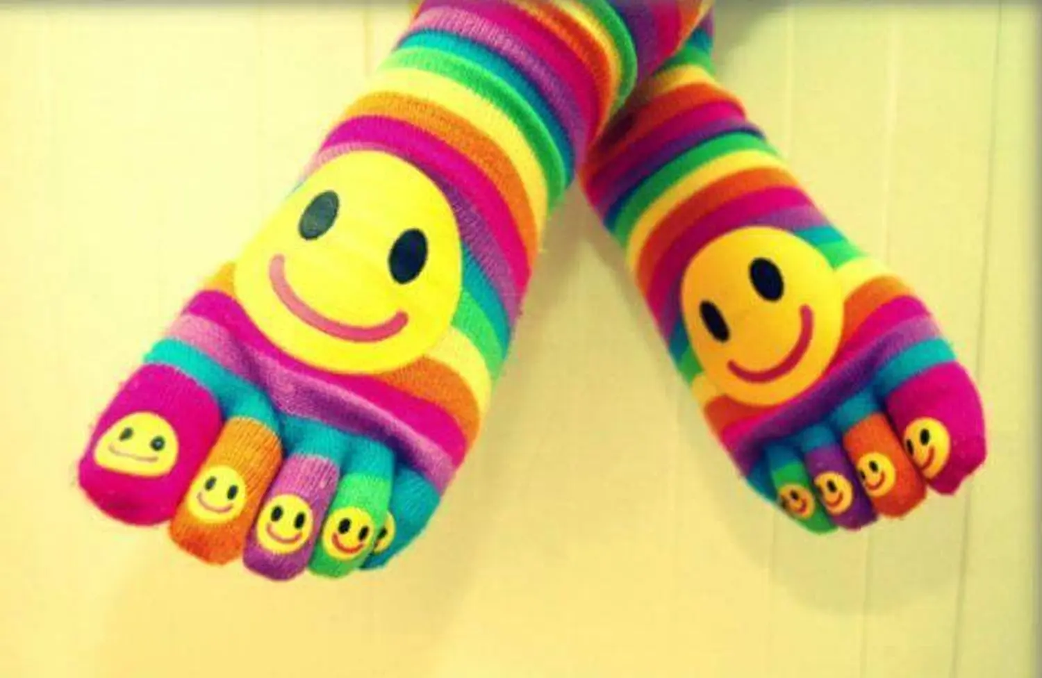 Füße mit regenbogenfarbenen Zehensocken mit Smileys